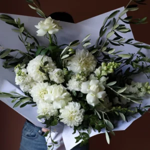 Bouquet of white flowers with olive foliage, reflexed roses, dahlias and snap dragons.