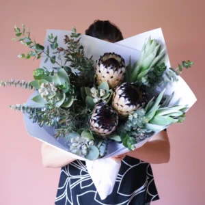 Vase arrangement of native flowers including queen proteas and tetragona gumnuts.